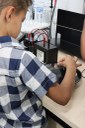 Menino olha com atenção holograma, enquanto acompanha explicação de como ele é formado