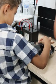 Menino olha com atenção holograma, enquanto acompanha explicação de como ele é formado