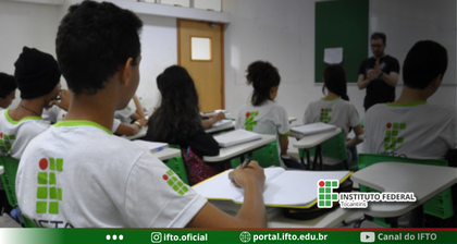 "Para cego ver": Sala de aula com estudantes usando o uniforme do IFTO concentrados em suas anotações e voltados para o professor, que fala à frente.
No canto inferior e no rodapé da imagem, aparecem a marca oficial e os canais de comunicação digitais do instituto.
